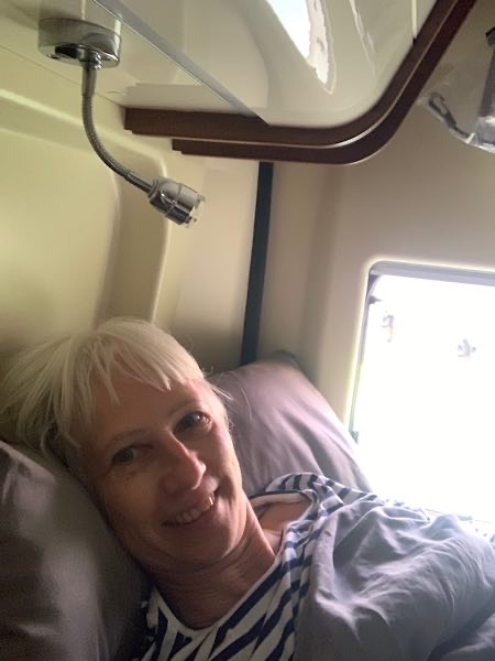 „Focusing-Coach Birgit Krüger liegt entspannt im Bett ihres Campers und lächelt in die Kamera – ein Moment des Innehaltens und Ankommens.“
