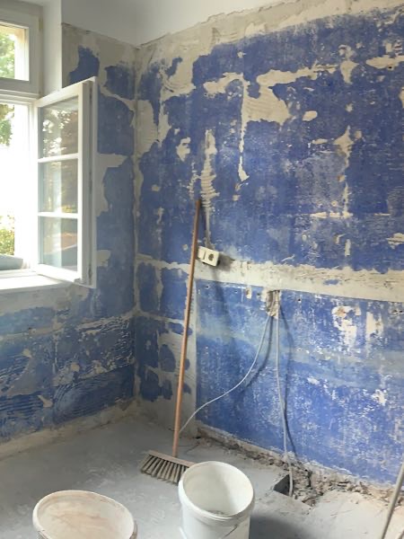 Leeres Bad, nachdem Fliesen entfernt wurden. Nun ist die alte blaue Wandfarbe zu sehen.