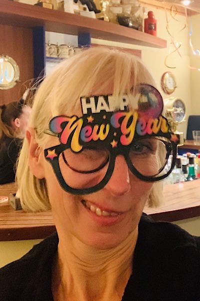 Frau mit weißem Haar und Happy-New-Year-Brille auf