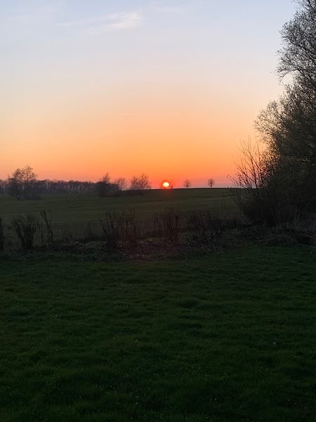 Sonnenuntergang über den Feldern bei der Steilküste von Boltenhagen – die untergehende Sonne taucht den Himmel in warmes Orange.