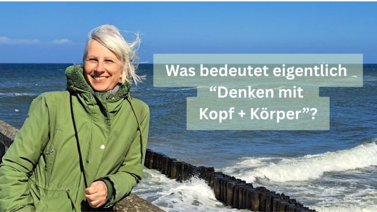 Birgit Krüger in grüner Jacke lächelt am windigen Meer; Text im Bild: „Was bedeutet eigentlich Denken mit Kopf + Körper?“